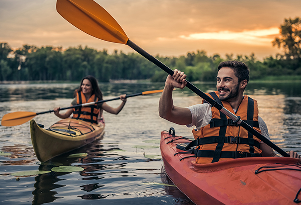 Happy young couple in sea vests is smiling while sailing kayaks